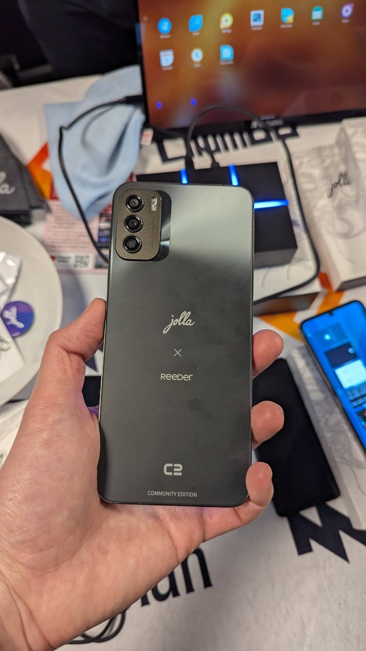 The Jolla x Reeder C2 Community Edition phone held up at the Linux on Mobile stand at FOSDEM 2025