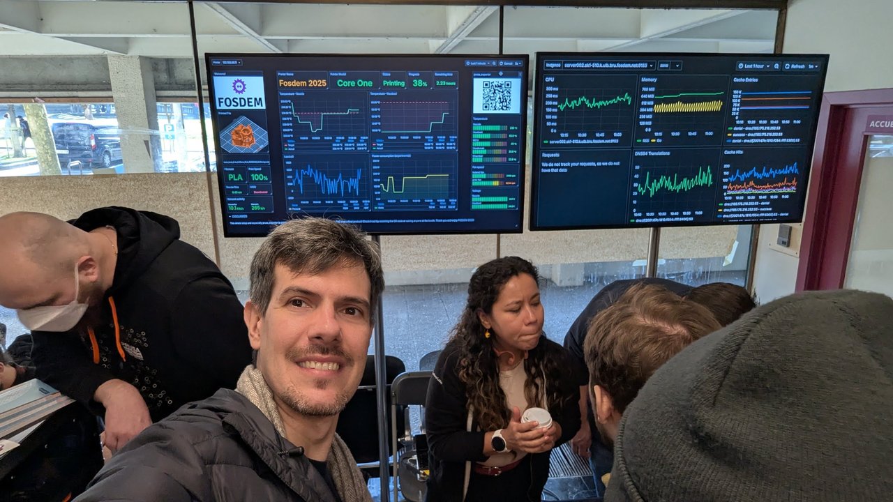 Luca Berton in front of a 3D printer dashboard showing a Prusa Core One printing a FOSDEM 2025 job
