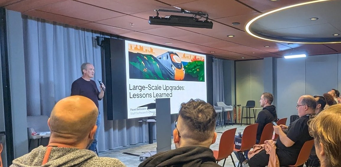The title slide Large-Scale Upgrades: Lessons Learned with a train illustration, with the speaker standing beside the screen