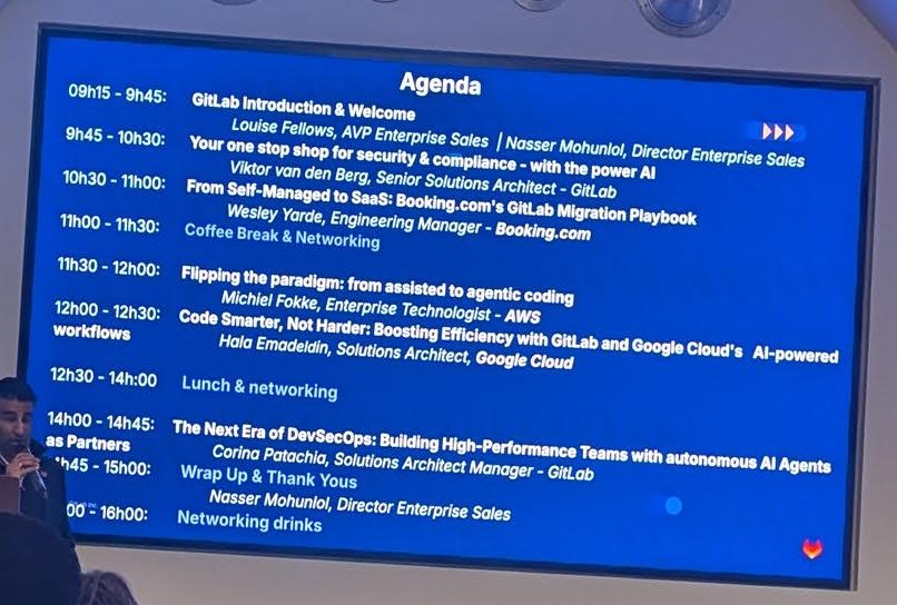 Epic Tour Amsterdam agenda slide listing sessions from 09h15 to 16h00 with speakers from GitLab, Booking.com, AWS and Google Cloud