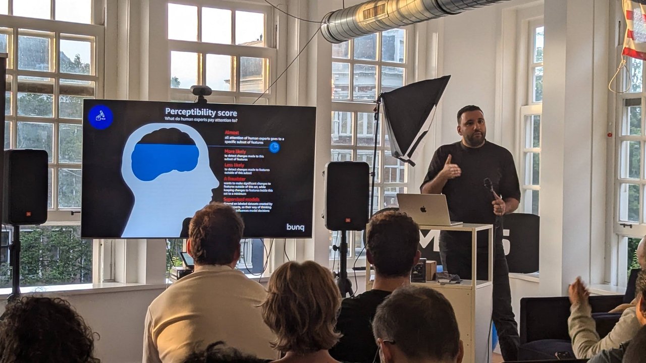 bunq's Perceptibility score slide asking what human experts pay attention to, with the speaker gesturing beside the screen