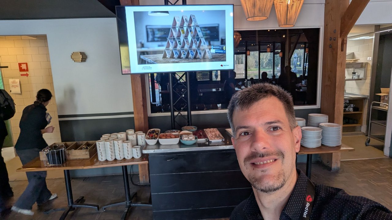 A slide showing a house of cards built from open source project logos, on a screen above the breakfast buffet at OpenShift Commons Gathering Amsterdam 2026
