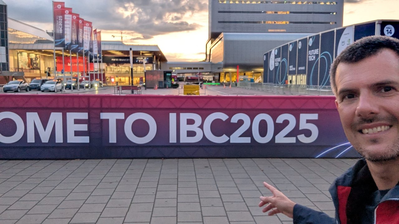 Luca Berton pointing at a long Welcome to IBC2025 banner in front of the RAI halls, with IBC2025 flags and the Future Tech hall behind