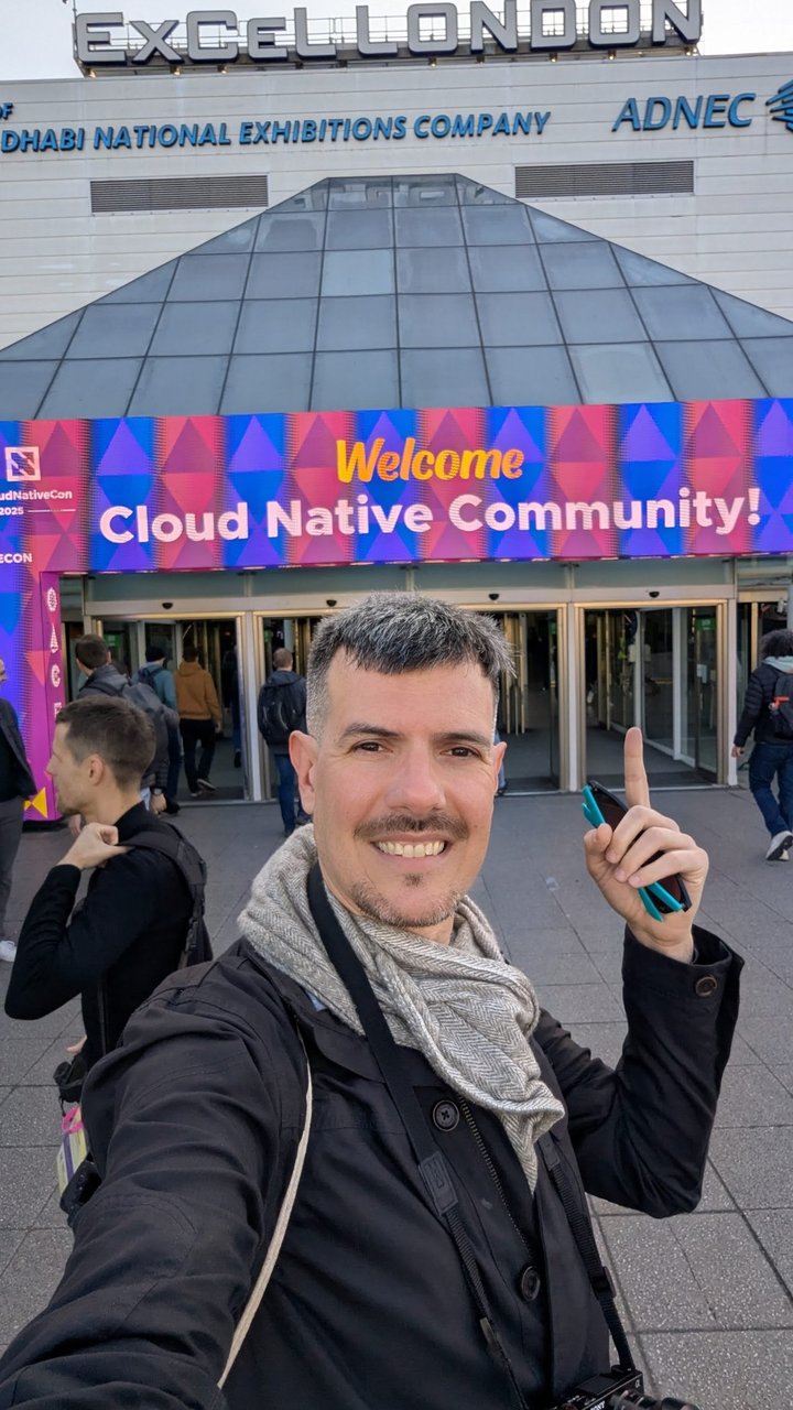 Luca Berton taking a selfie in front of the ExCeL London entrance with a Welcome Cloud Native Community banner
