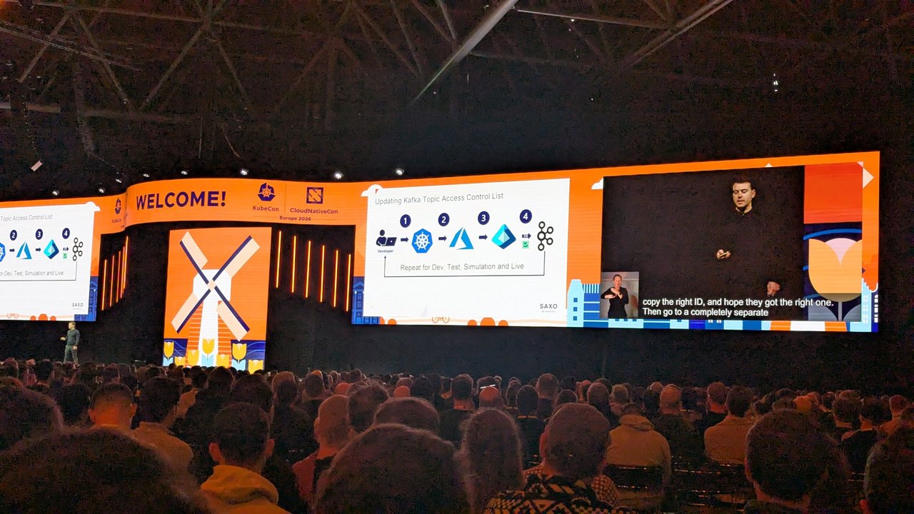 A Saxo keynote slide at KubeCon Europe 2026 titled Updating Kafka Topic Access Control List, showing four manual steps repeated for Dev, Test, Simulation and Live