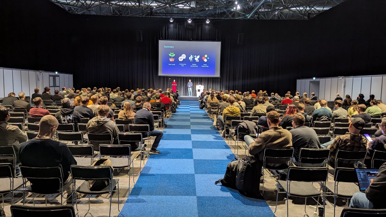 Platform Engineering Day Europe 2026 audience at RAI Amsterdam watching the Golden Path as a Product summary slide: start small, community first, defeat bureaucracy, solve shared pain