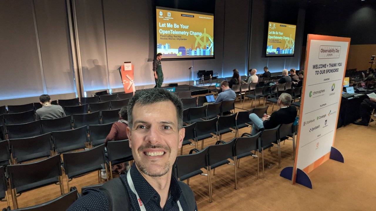 Luca Berton in the Observability Day Europe 2026 room at RAI Amsterdam before the Let Me Be Your OpenTelemetry Champ talk, with the sponsor board on the right