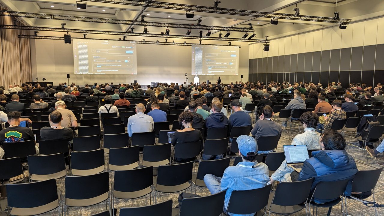 A packed co-located session hall at RAI Amsterdam on Monday afternoon, with attendees facing several screens