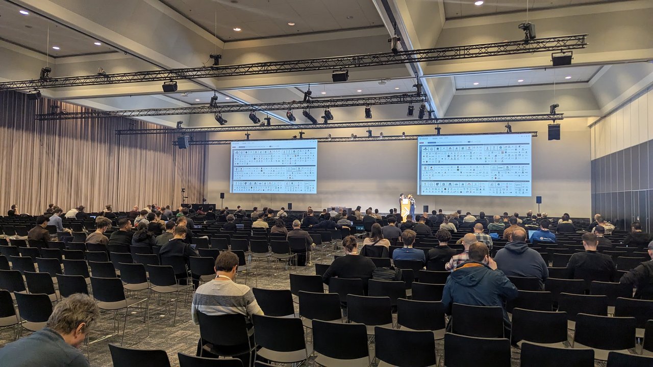 A co-located event room at RAI Amsterdam on Monday 23 March, with rows of attendees facing two large screens