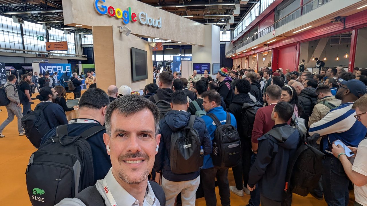Luca Berton taking a selfie in a dense crowd on the KubeCon Europe 2026 expo floor, with the Google Cloud stand behind him