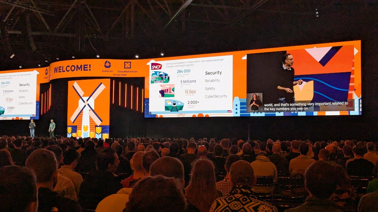 The KubeCon + CloudNativeCon Europe 2026 keynote stage at RAI Amsterdam with a windmill welcome graphic and a packed audience