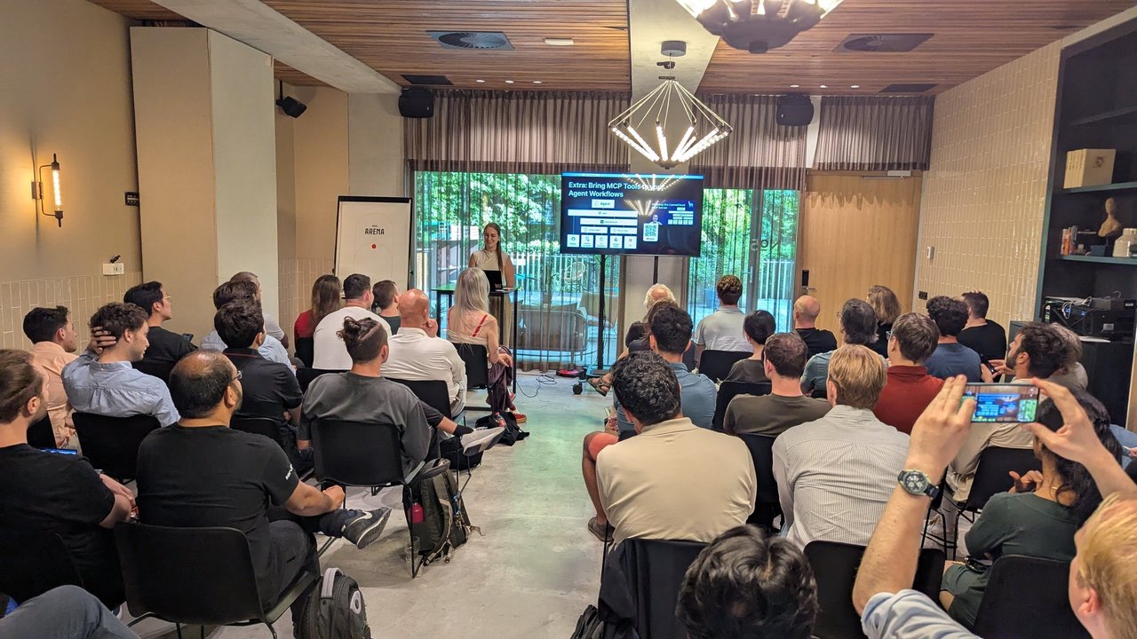 Wide shot of the room with a speaker at the front and a slide titled Extra: Bring MCP Tools to your Agent Workflows