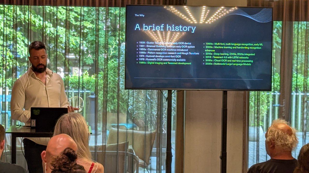 Speaker next to a slide titled A brief history listing OCR milestones from 1929 to the 2020s