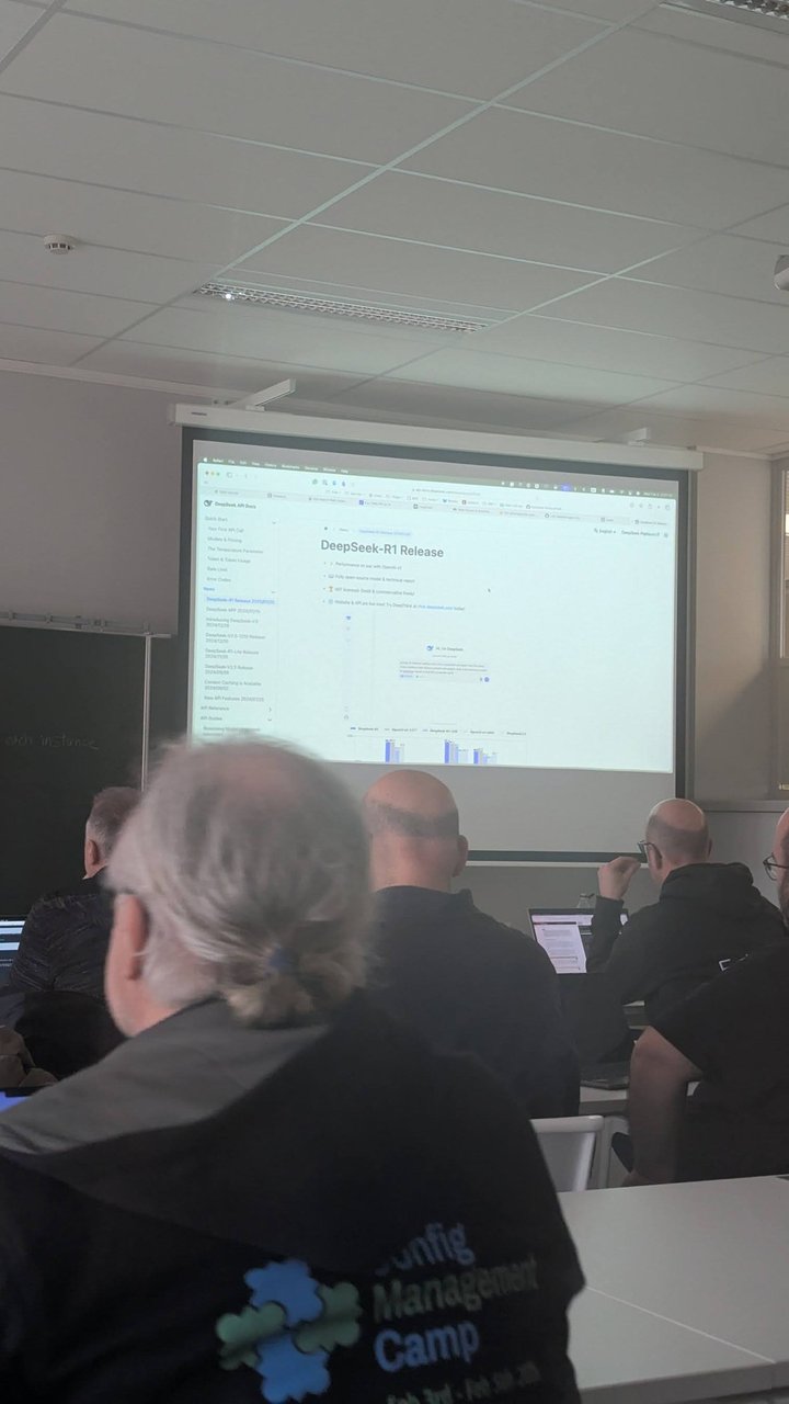 A projected browser page titled "DeepSeek-R1 Release" in the CfgMgmtCamp 2025 workshop room, viewed from behind an attendee wearing a Config Management Camp hoodie