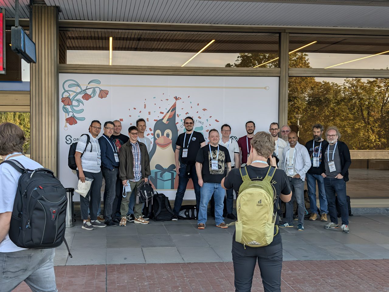 Attendees posing for a group photo in front of the 35 years of Linux wall