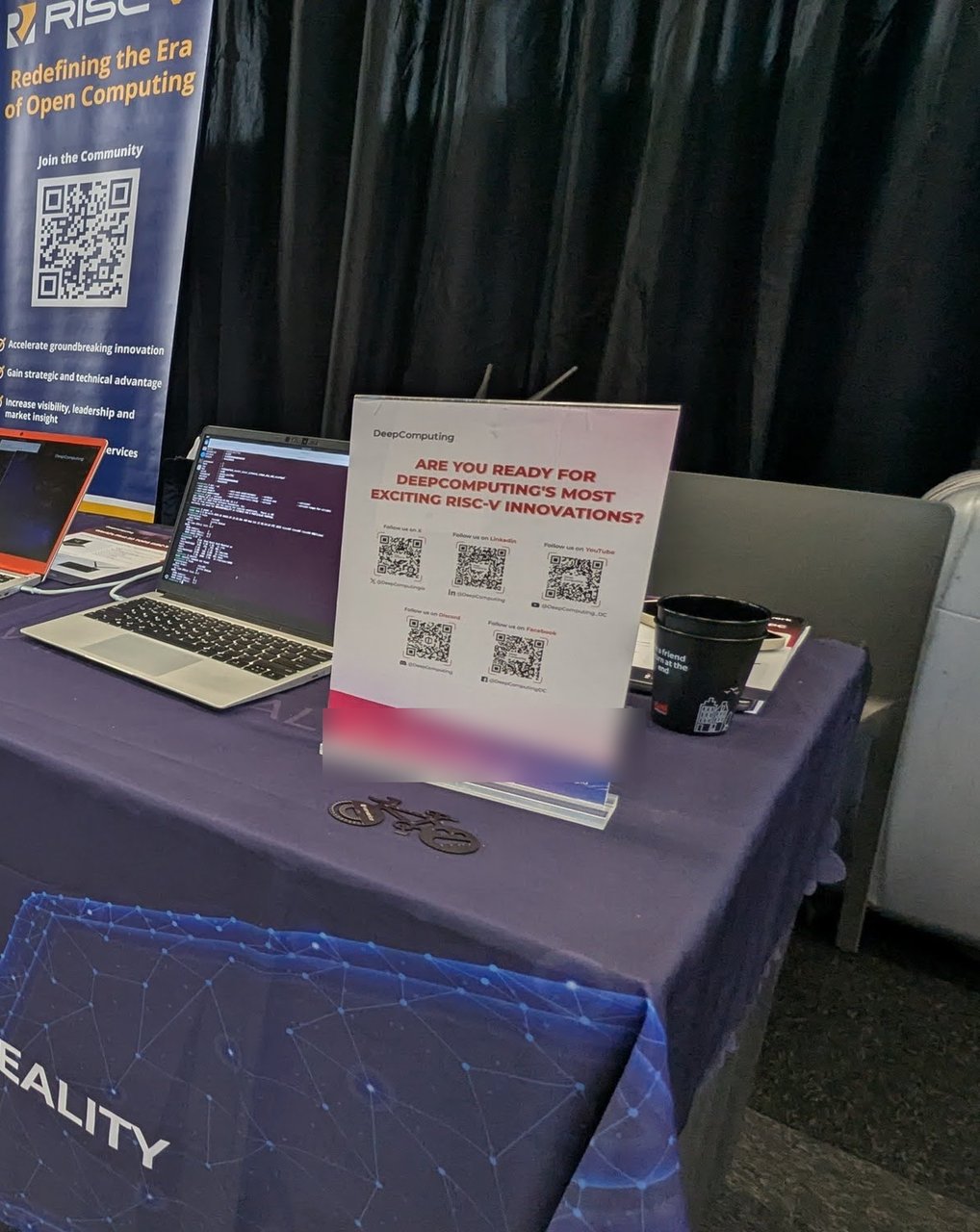 The RISC-V booth at Open Source Summit Europe 2025 on Tuesday: the RISC-V Redefining the Era of Open Computing banner, DeepComputing laptops running a Linux terminal, and the Turning RISC-V into Reality tablecloth