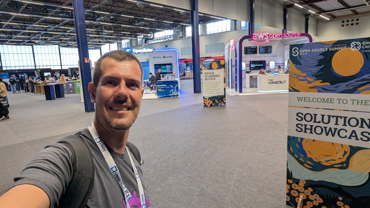 Luca Berton taking a selfie at the entrance of the Open Source Summit Europe 2025 Solutions Showcase at RAI Amsterdam, with the openEuler and AWS open source booths behind him