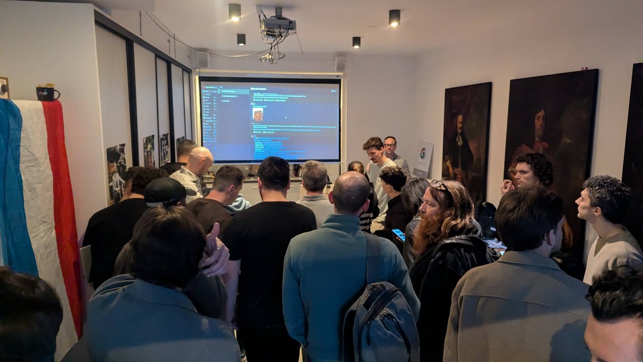 Builders crowding around the projector screen during a demo at the OpenClaw Demo + Hackathon Amsterdam