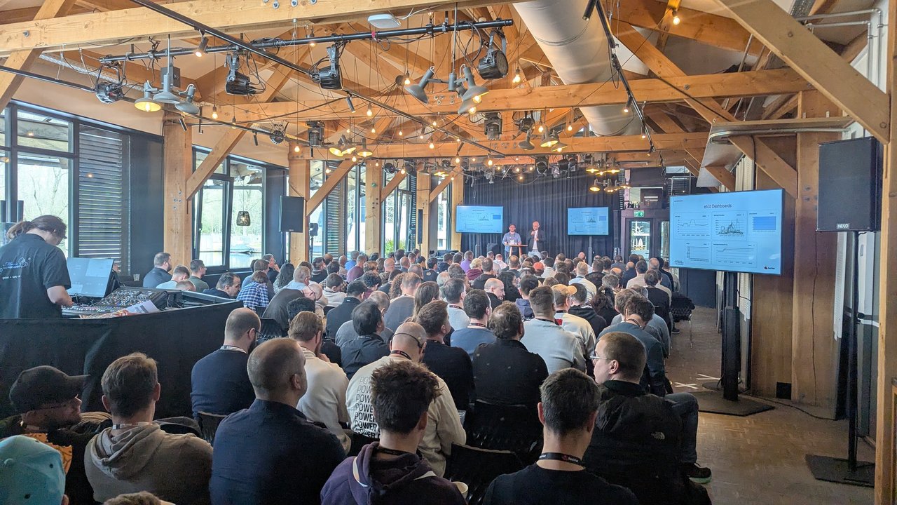 Two speakers presenting the etcd Dashboards slide to a full room at OpenShift Commons Gathering Amsterdam 2026