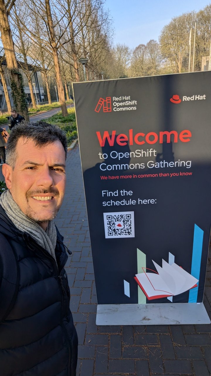 Luca Berton next to the OpenShift Commons Gathering welcome sign outside Strandzuid in Amsterdam, with the tagline We have more in common than you know