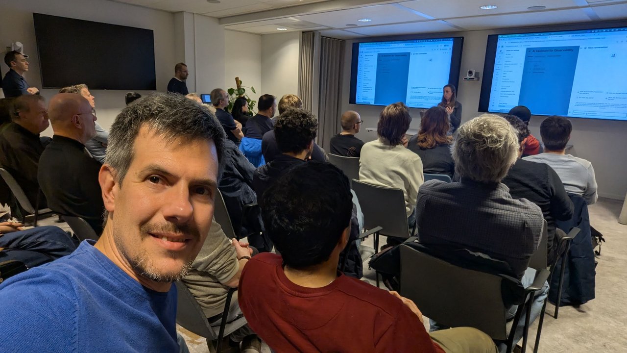 Luca Berton in the audience at the SRE NL meetup at Elastic Amsterdam during the OpenTelemetry talk, with the speaker and two screens in the background