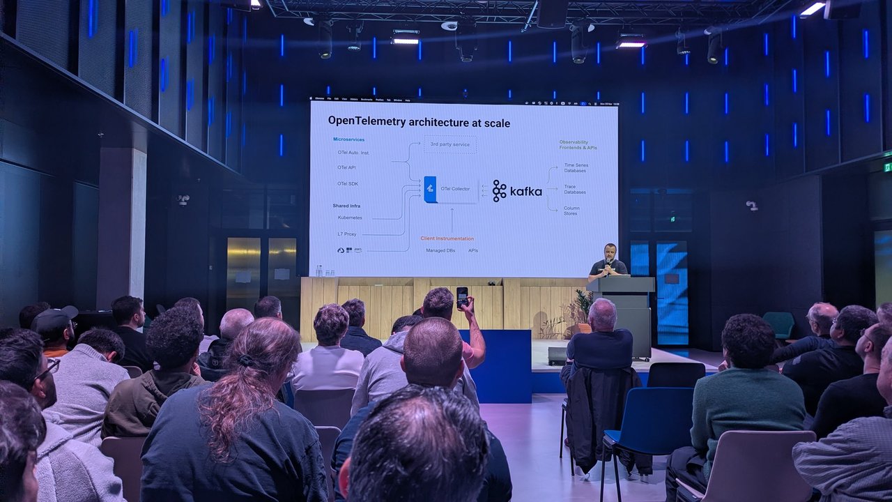 Slide titled OpenTelemetry architecture at scale at Signal Overflow, with microservices, Kubernetes, an L7 proxy and cloud services feeding an OTel Collector and Kafka, then time series, trace and column stores