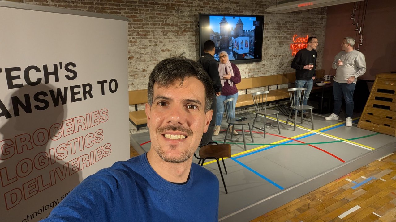 Luca Berton next to the Picnic Tech's answer to groceries, logistics, deliveries banner at the developer experience meetup in Amsterdam