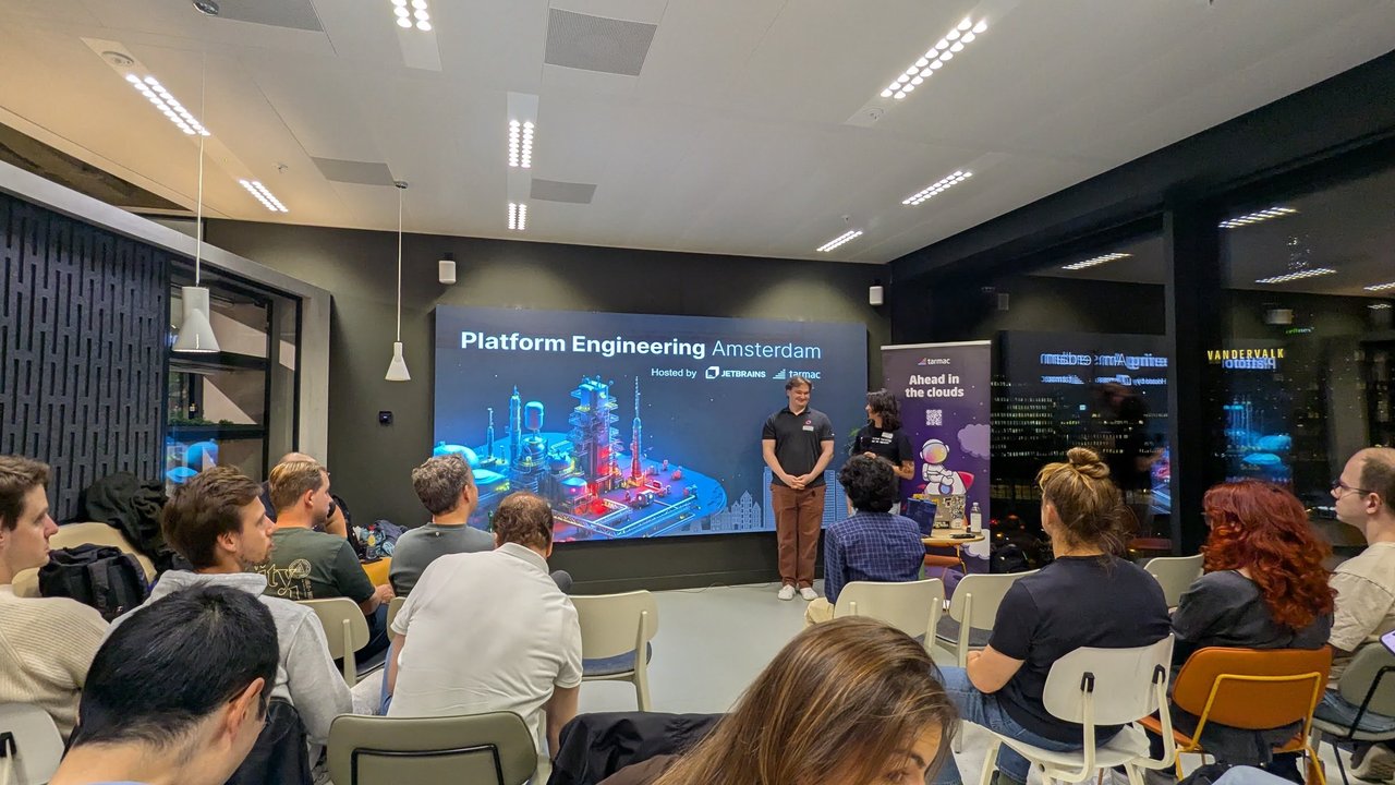 Platform Engineering Amsterdam opening slide hosted by JetBrains and tarmac, with the Ahead in the clouds roll-up and the audience seated