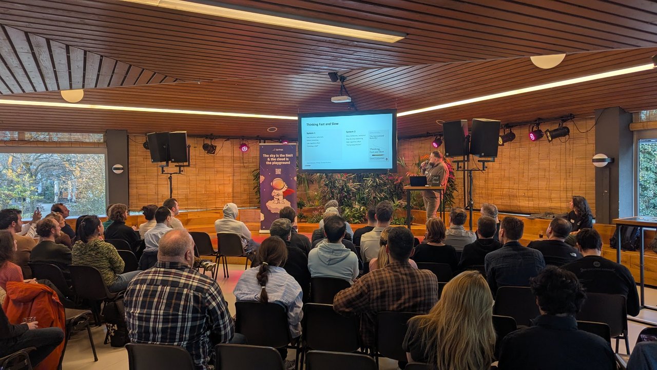 Wide view of the Tolhuistuin room during the Coder talk, with the Thinking Fast and Slow slide comparing System 1 and System 2 on screen