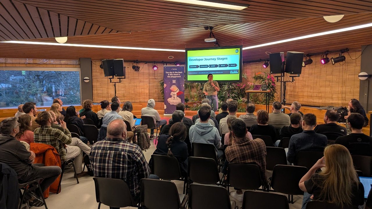 Lian on stage in front of the Developer Journey Stages slide showing Discover, Evaluate, Learn, Build and Scale, with the audience in the foreground