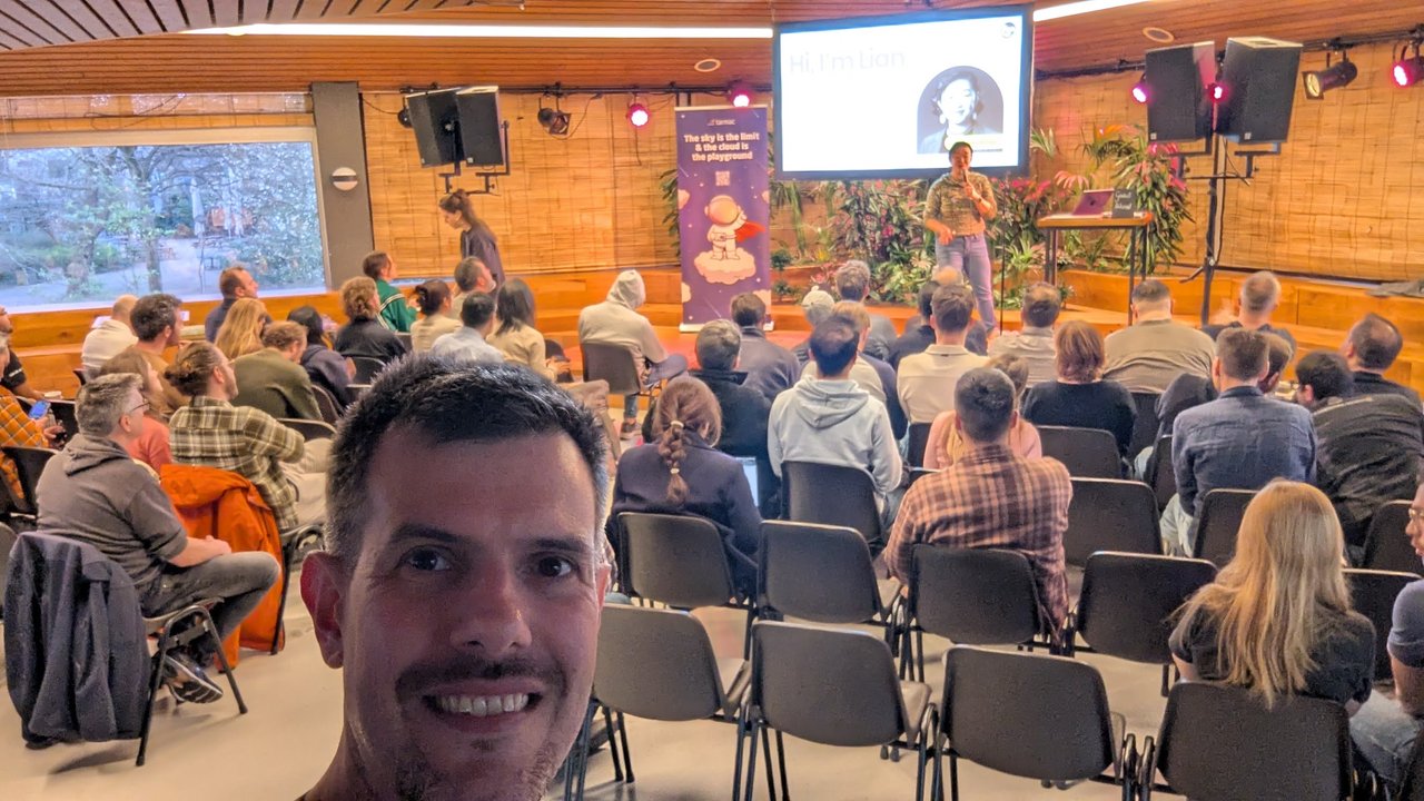 Selfie of Luca in the audience while Lian presents her "Hi, I'm Lian" intro slide at the front of the room
