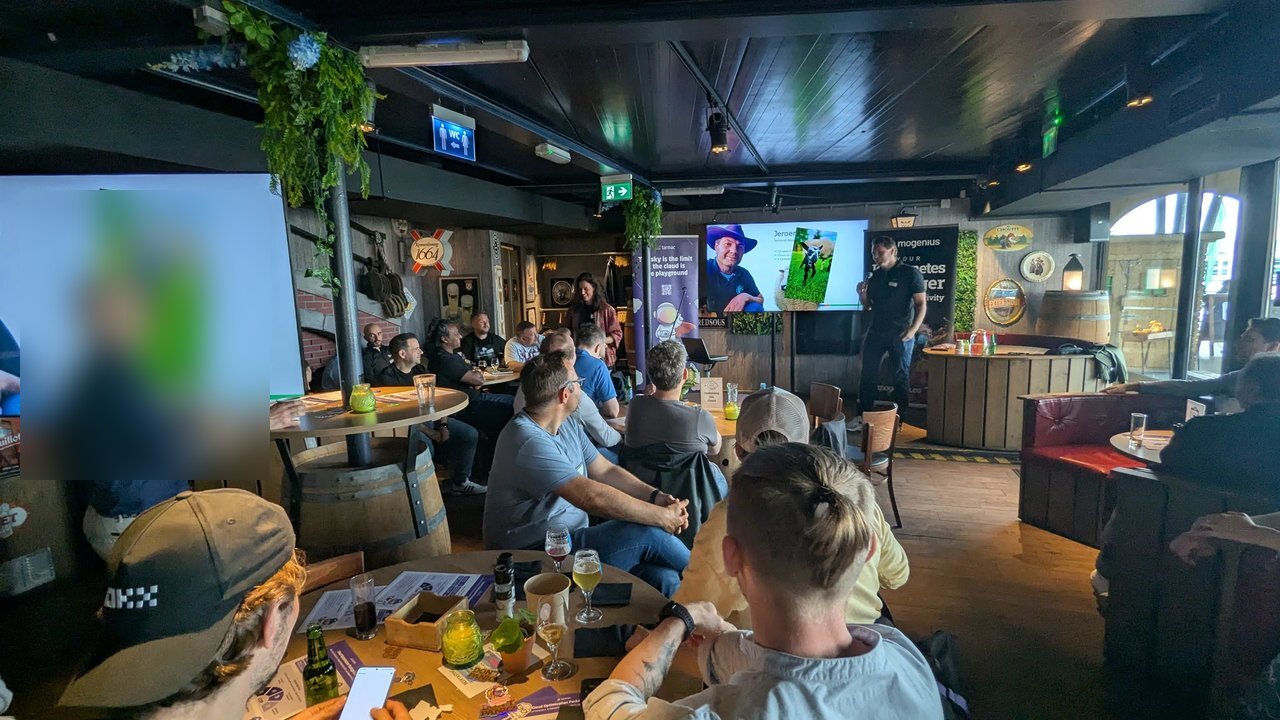 The room at Platform Engineering Amsterdam with the speaker's introduction slide on the screens and the tarmac and mogenius banners