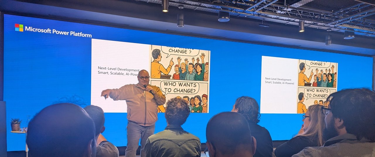 The host standing in front of a cartoon slide titled Who wants to change at the Microsoft Power Platform meetup