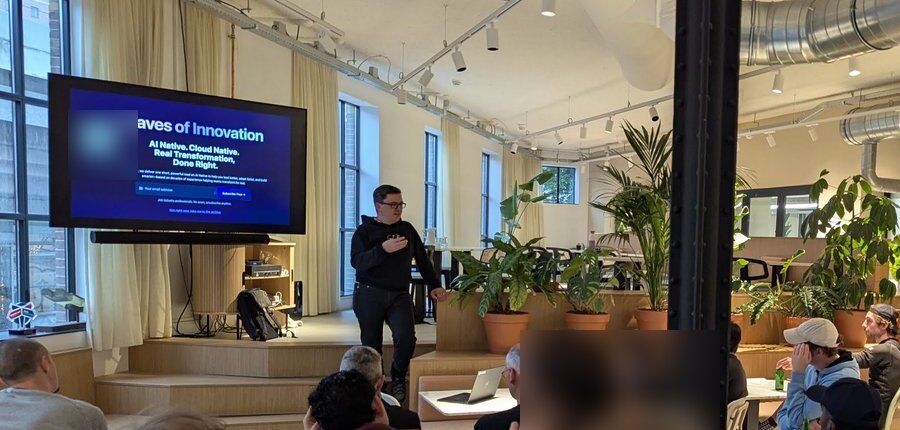 The Waves of Innovation slide on the screen while the presenter speaks, with pizza boxes on the tables