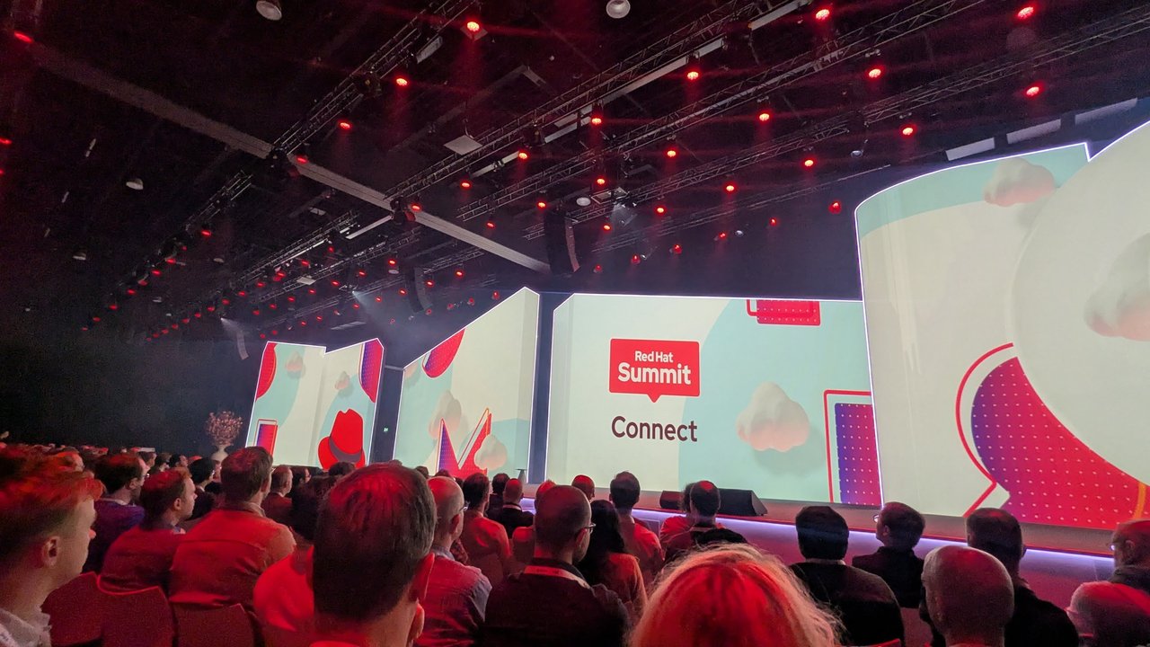 The main hall at Red Hat Summit Connect 2025 just before the keynote, with a full audience and Red Hat Summit Connect on the video walls