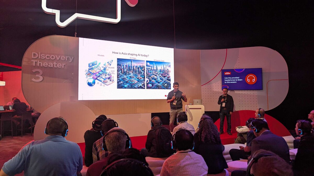 Wide shot of Discovery Theater 3 — packed audience with headphones at Red Hat Summit