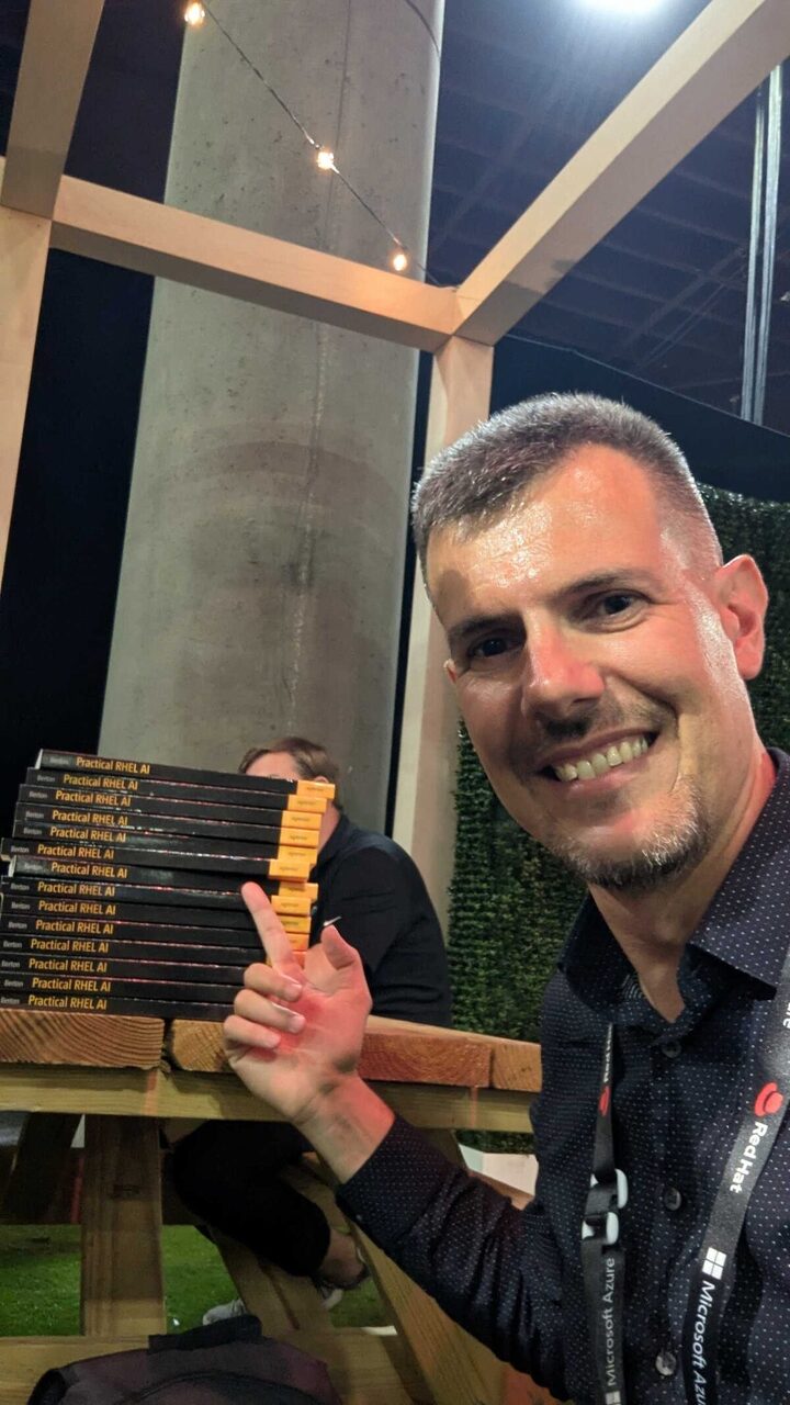 Luca Berton with the book stack ready for giveaway at Red Hat Summit 2026