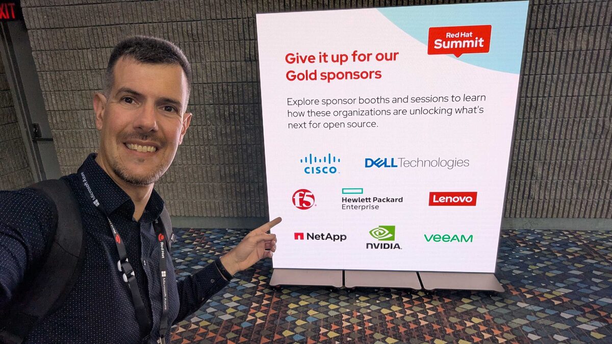 Luca Berton at Red Hat Summit 2026 with Gold Sponsors board — Cisco, Dell, F5, HPE, Lenovo, NetApp, NVIDIA, Veeam