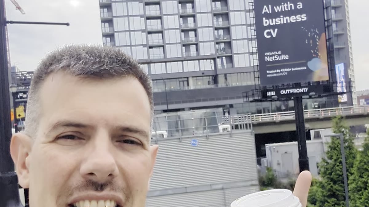 Luca Berton in front of an Oracle NetSuite "AI with a business CV" billboard in Atlanta during Red Hat Summit 2026