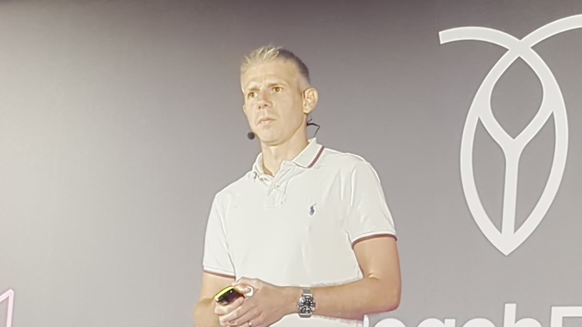 An engineer speaking on stage in front of the RoachFest logo at RoachFest London 2026, recounting a real GCP outage