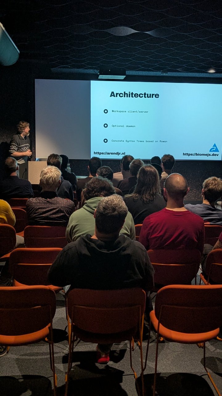 Portrait photo of the Biome Architecture slide: workspace client/server, optional daemon, concrete syntax trees based on Rowan