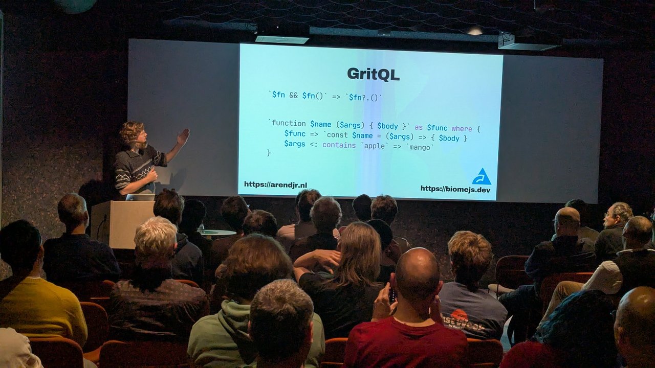 The GritQL slide with two rewrite patterns, the speaker gesturing at the screen