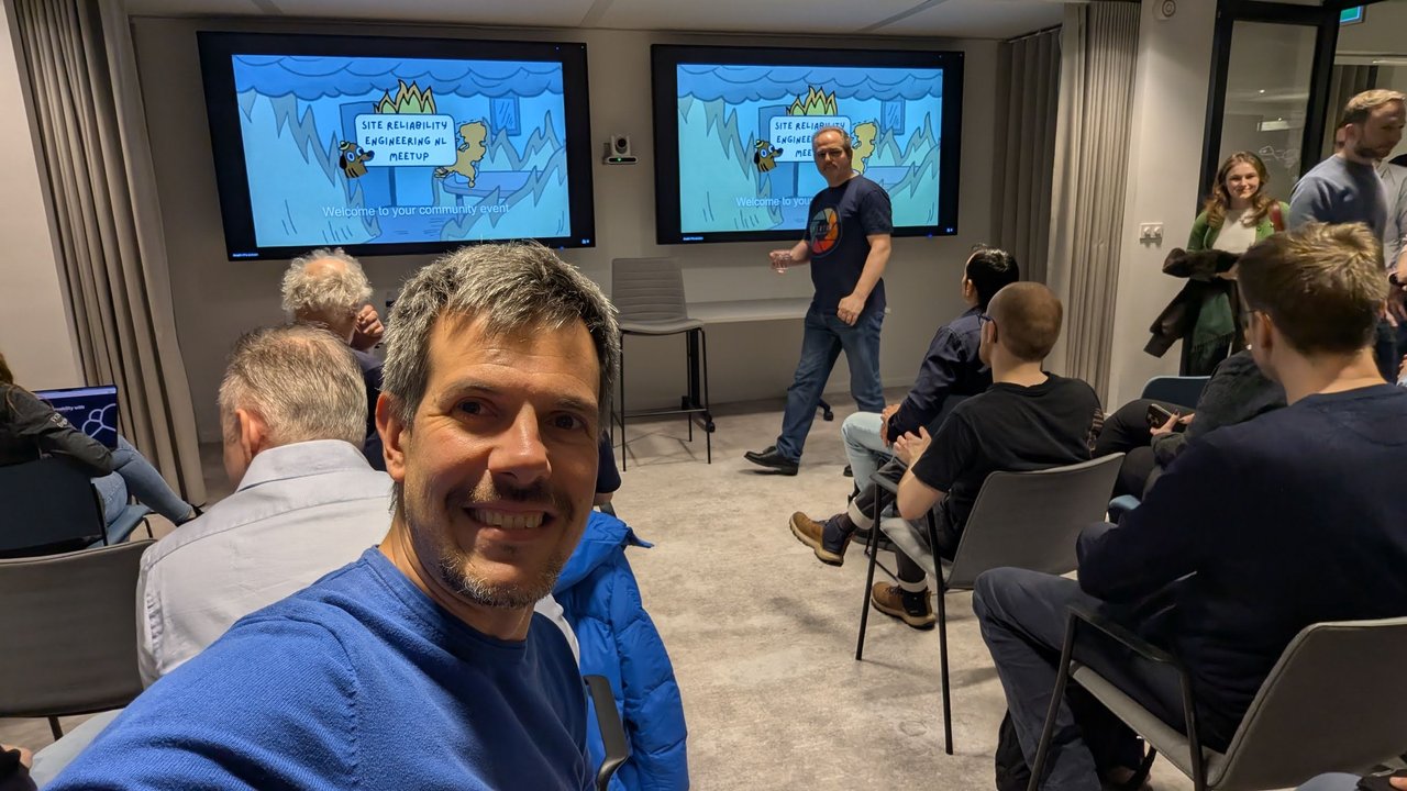 Luca Berton in the audience at the SRE NL meetup at Elastic Amsterdam, with the Welcome to your community event slide on both screens