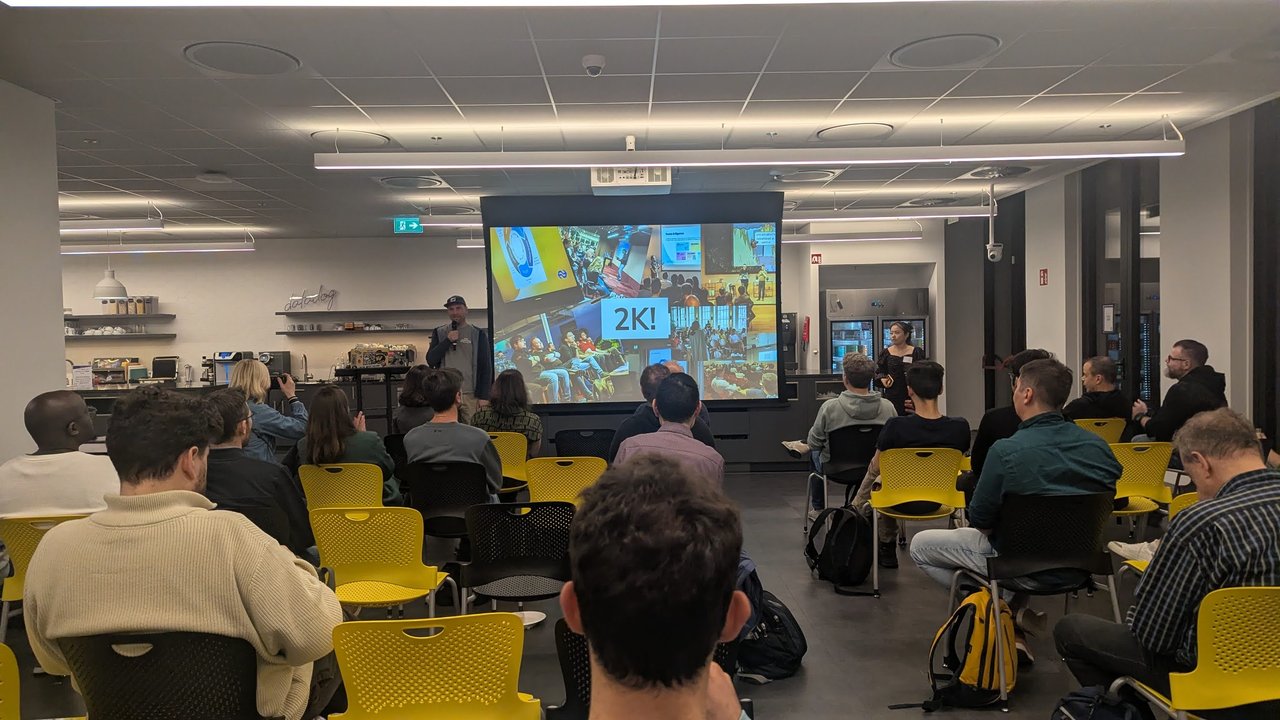 The SRE NL organiser on stage next to a 2K! slide over a collage of past meetup photos