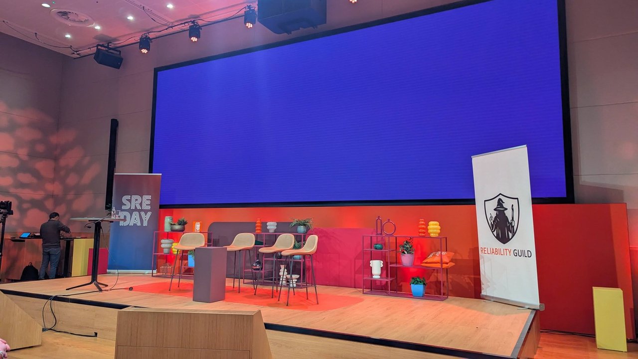 The SREday main stage before the first talks, with an SRE DAY banner, a Reliability Guild banner and an empty speaker table