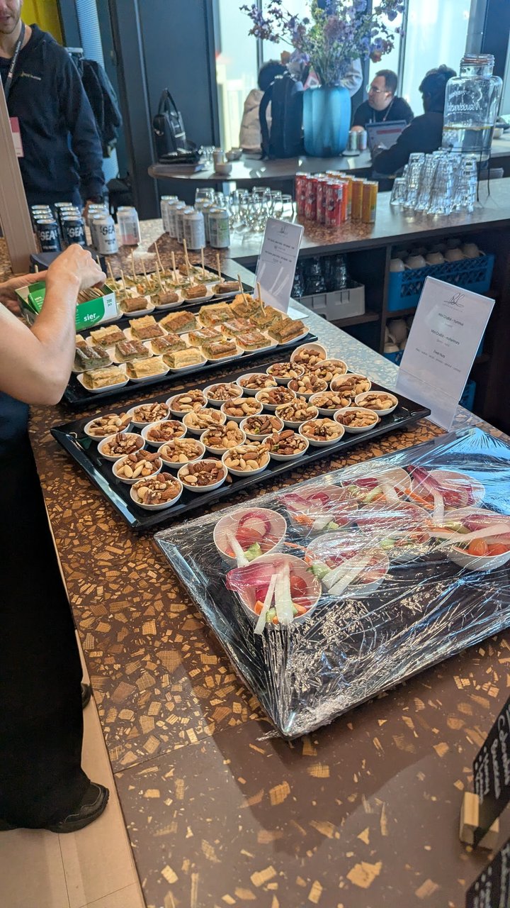 Afternoon break at Cloud Native Rejekts 2026 at Miro HQ, with trays of pastries on a counter next to the Rejekts sponsor banner