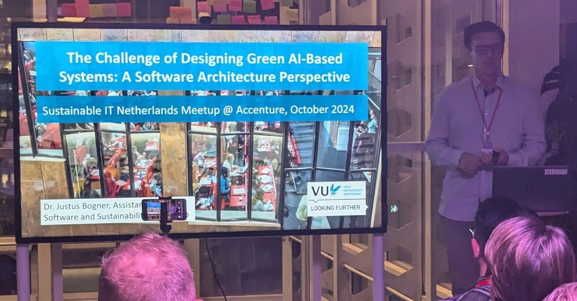 Title slide "The Challenge of Designing Green AI-Based Systems: A Software Architecture Perspective" at the Sustainable IT Netherlands Meetup at Accenture, with the speaker beside the screen