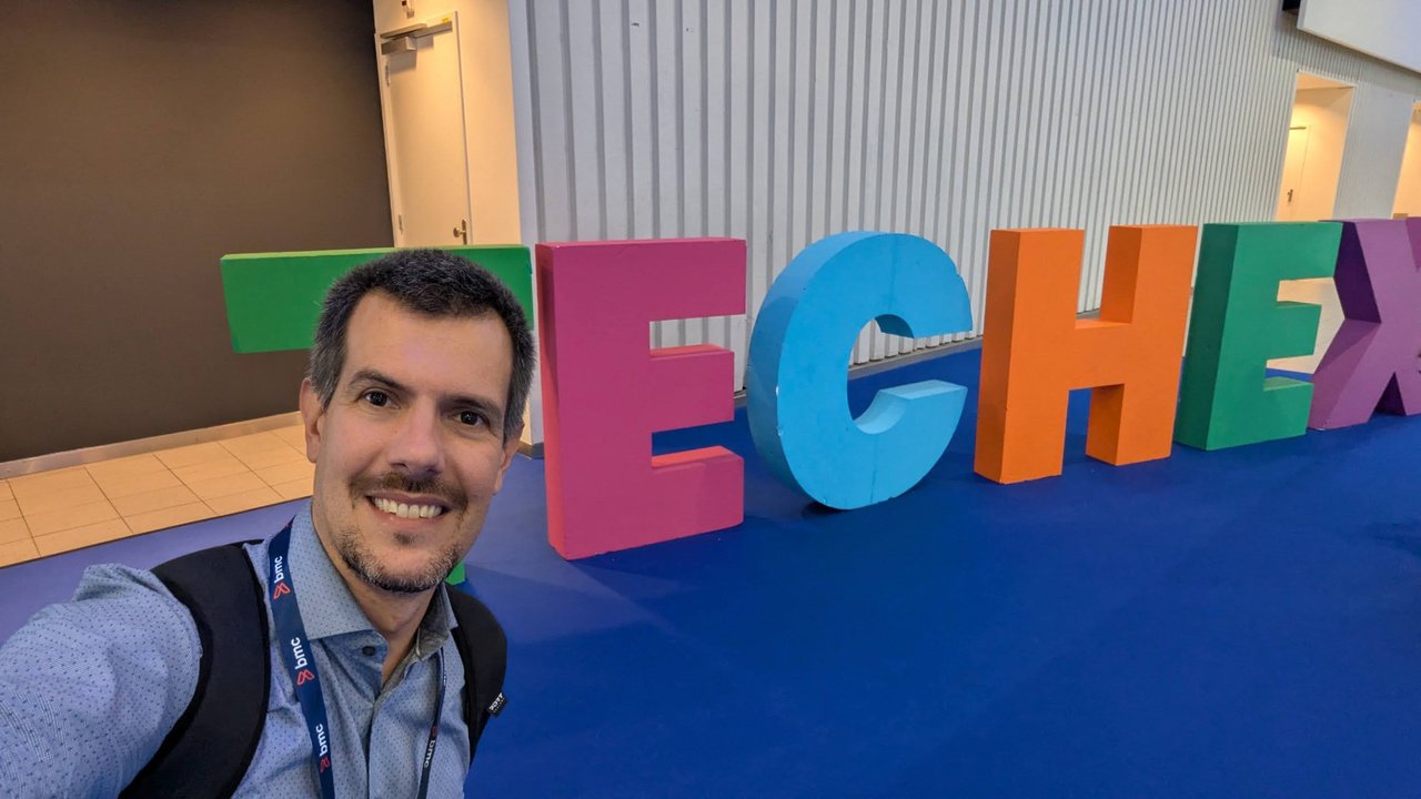 Luca Berton taking a selfie in front of giant colourful TECHEX letters on a blue carpet at the RAI