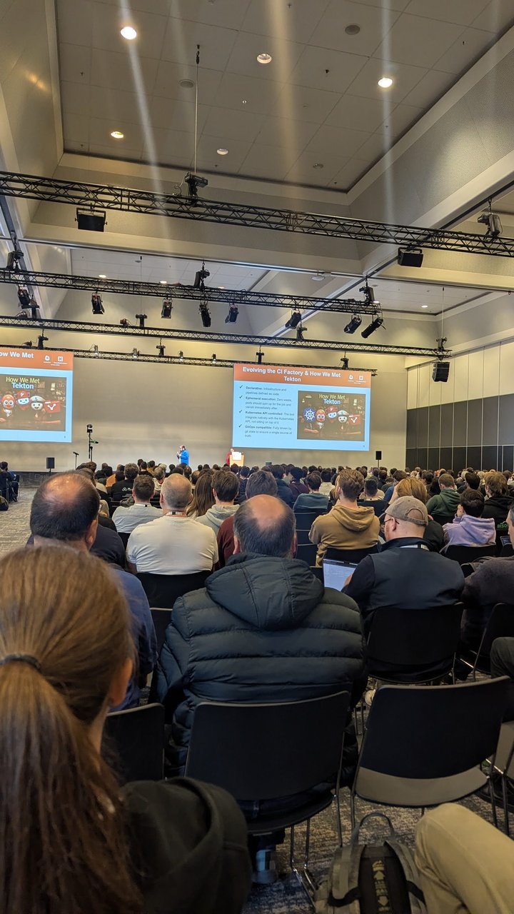The KubeCon Europe 2026 breakout room for the Tekton CI factory talk, with the slide Evolving the CI Factory and How We Met Tekton on the screens