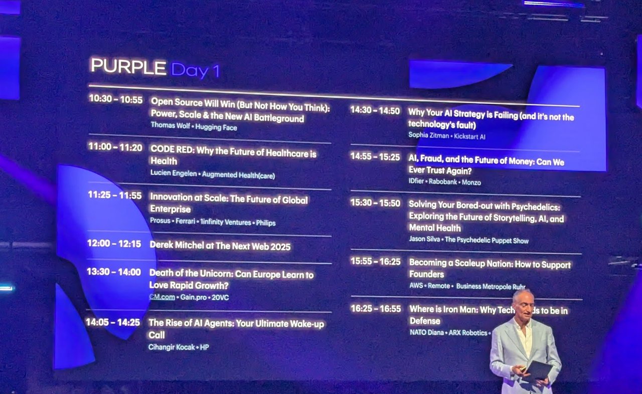 PURPLE Day 1 agenda on the TNW Conference 2025 main stage screen, listing sessions from 10:30 to 16:55 with a presenter standing on the right